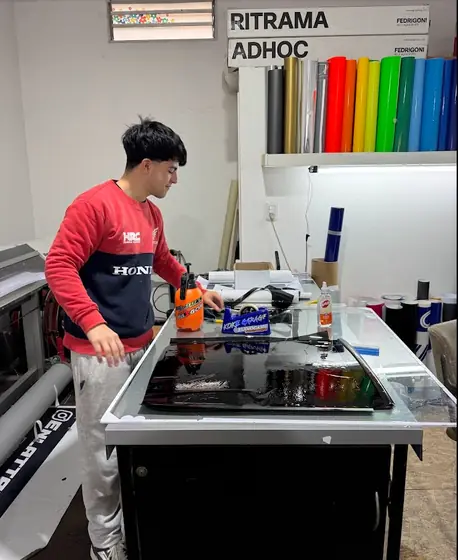 Trabajando en el taller de Gráfica Roca, con rollos de vinilo de colores de fondo